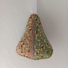 an ornament hanging from the side of a wall with leaves and berries on it