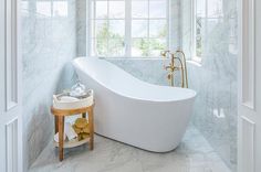 a white bath tub sitting inside of a bathroom next to a window