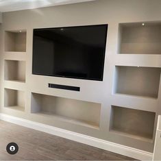 a flat screen tv mounted to the side of a wall in a living room with built - in shelving