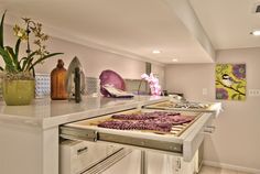 a kitchen with an oven, stove and counter top covered in purple flowers next to potted plants