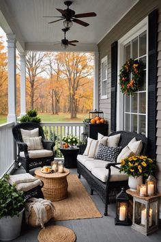 an outdoor porch with wicker furniture and candles on the table, surrounded by fall foliage