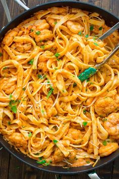 pasta with shrimp and parsley in a skillet on a wooden table, ready to be eaten