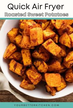 a white bowl filled with roasted sweet potatoes on top of a wooden table and text overlay reads quick air fryer roasted sweet potatoes