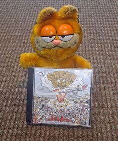 a stuffed animal holding a cd case with the cover on it's face and eyes