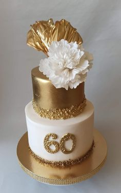 a three tiered cake with gold and white flowers on it's top layer