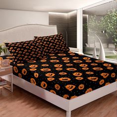 a bed with black and orange pumpkins on it