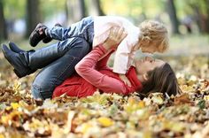 a woman and child laying on the ground with leaves in front of their faces,