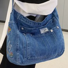 a person holding a blue jean purse over their shoulder