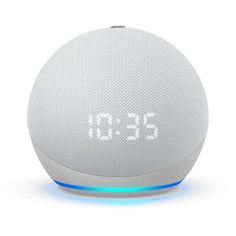 an alarm clock sitting on top of a white table next to a bluetooth speaker