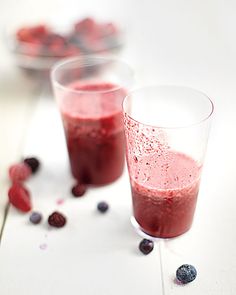 two glasses filled with berry smoothie on top of a table