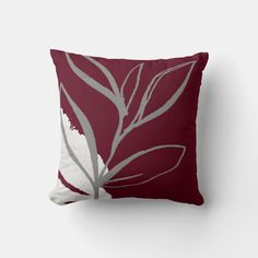 a red pillow with white and grey leaves on the front, along with text that reads burgundy & gray minimalist water by design home