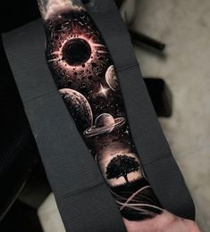 a man's arm covered in tattoos with planets and trees