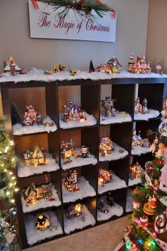 a christmas display in the corner of a room with many ornaments on shelves and trees