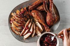 a person holding a spoon near a plate with sliced turkey and cranberry sauce