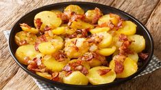 a pan filled with potatoes and bacon on top of a wooden table