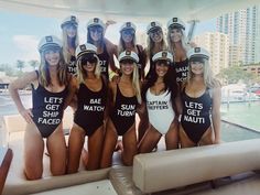 a group of women in swimsuits posing for a photo on a boat at the beach