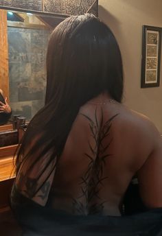 the back of a woman's body is shown in front of a mirror, with tattoos on it