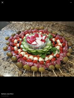 a platter filled with cucumbers, olives and meat on skewers