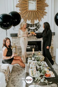 two women sitting on couches in front of a table with food and drinks, talking to each other