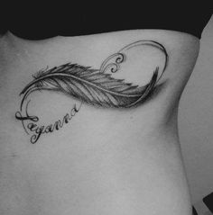 a black and white photo of a woman's stomach with a feather tattoo on it