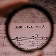 a sheet music with the words she loves you through a magnifier lens