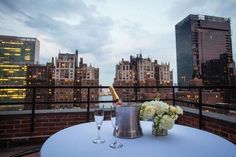 two champagne flutes are sitting on a table with flowers in front of the city skyline