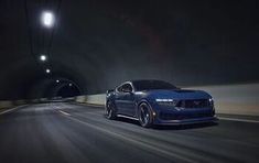 a blue car driving through a tunnel in the dark night with its headlights turned on