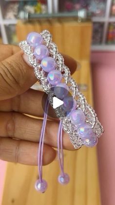 a person holding a purple bracelet with beads