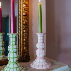 three candles are sitting on a table in front of a mirror and an ornate frame