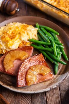 a plate with ham, green beans and mashed potatoes next to a casserole dish