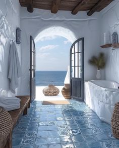 an open door leading into a bathroom with blue tile flooring and walls, overlooking the ocean