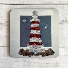 a white frame with a red, white and blue christmas tree made out of buttons