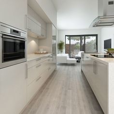 a modern kitchen with wood floors and stainless steel appliances, along with an open floor plan