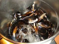 some mussels are being cooked in a pot on the stove top with boiling water