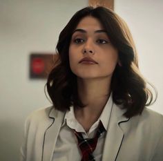 a woman wearing a suit and tie in an office setting, looking off to the side