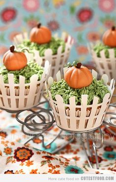 some cupcakes with green and orange frosting on them are sitting on a table