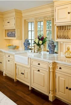 a large kitchen with yellow cabinets and white counter tops, along with wooden flooring