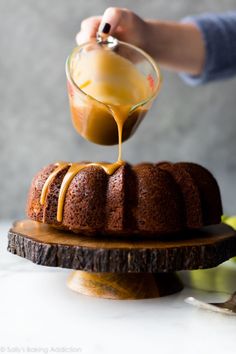 someone pouring caramel sauce on top of a bundt cake