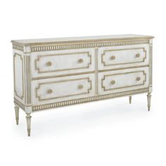 an antique white dresser with gold trimmings on the top and drawers, in front of