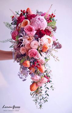 a woman holding a bouquet of pink and red flowers in her hand with white background