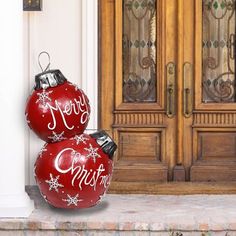 two red christmas ornaments sitting in front of a door