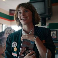 a woman holding up a book in front of her face and smiling at the camera