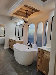 a large white bath tub sitting inside of a bathroom next to two sinks and mirrors