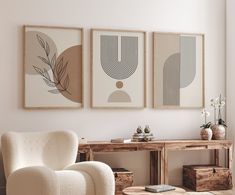 three framed art pieces hang on the wall above a white chair in a living room