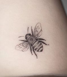 a small tattoo of a bee on the back of a woman's stomach,