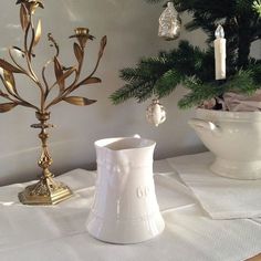 a white vase sitting on top of a table next to a candle holder and christmas tree