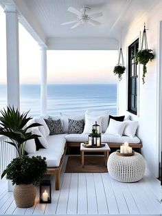 an outdoor living area with white furniture and plants on the porch next to the ocean