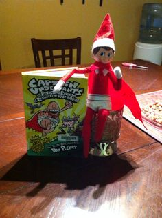 an elf is sitting on the table next to a box of cereal and a pizza