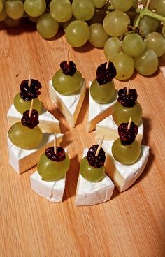 grapes and cheese are arranged on small pieces of paper with toothpicks in the middle