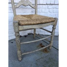 an old wooden chair with wicker seat and back rests against a brick wall in front of it